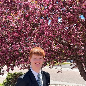 A student poses for a picture in front of a pink tree